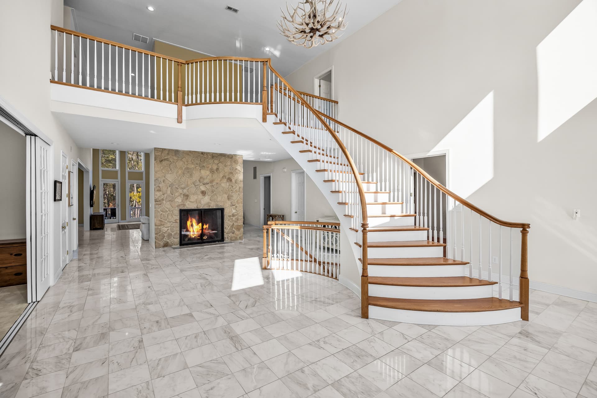 Bright two-story entry with a curved staircase and fireplace in a Marlton, NJ home