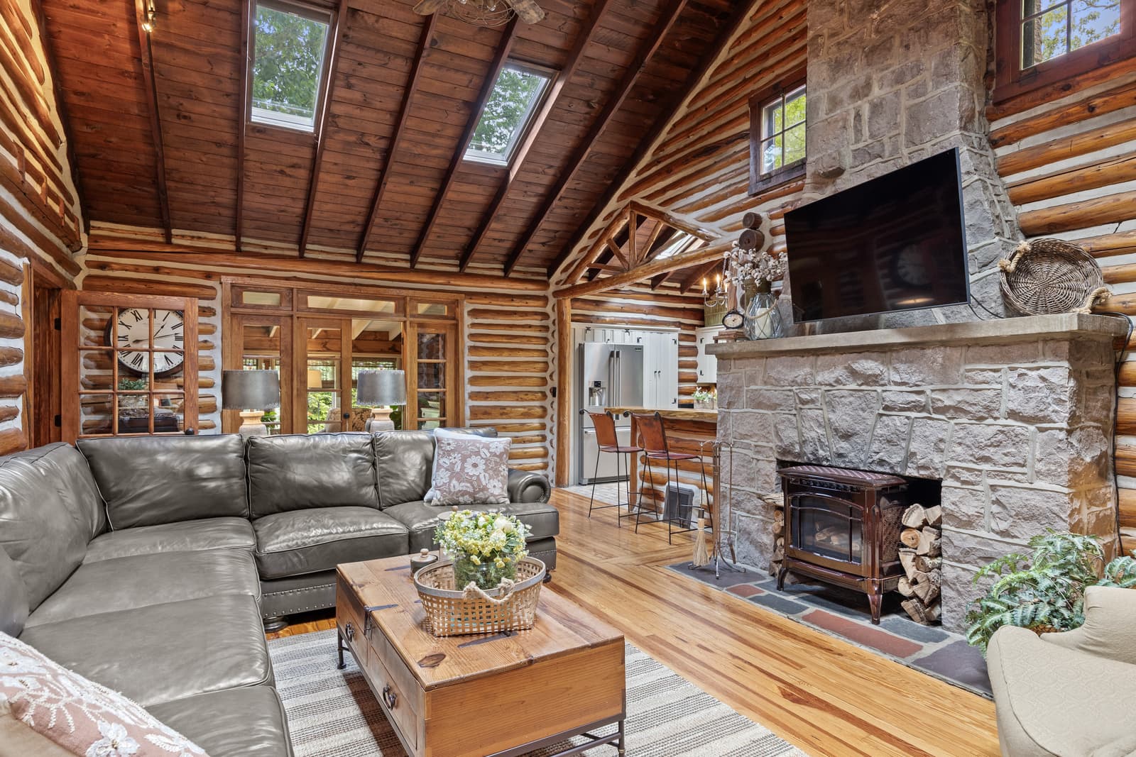 Log cabin living room with a stone fireplace and wood-beam ceiling in Medford, NJ