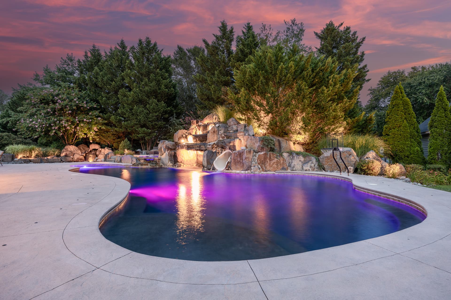 Twilight photography of a freeform pool with color LED lighting at dusk, South Jersey